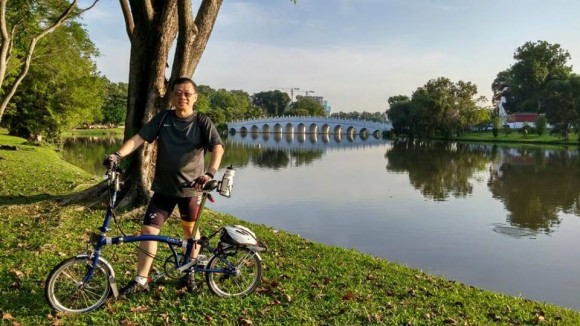 Chinese garden Pastor Richard Wong posing with his Brompton and with Chinese Garden in the background